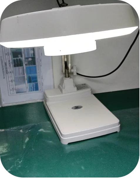 Folding magnifying lamp installed at trimming workstation